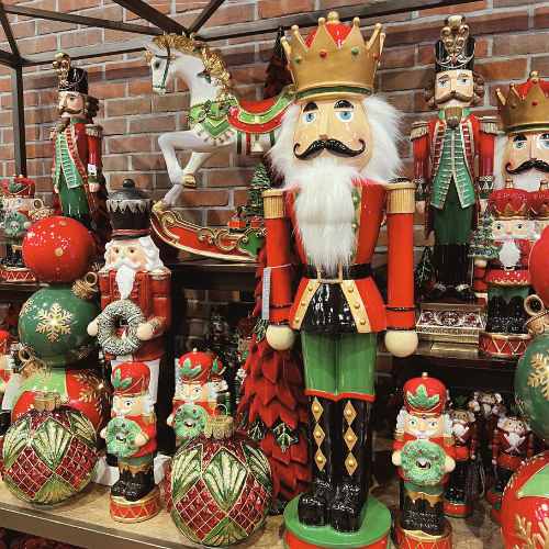 Christmas Decor Nutcrackers A festive display of colorful nutcracker figurines, Christmas ornaments, and a decorative rocking horse set against a brick wall, creating a cheerful holiday scene.