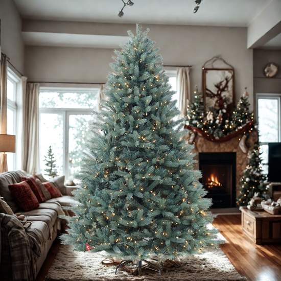 A large, pre-lit artificial Christmas tree with blue-tinted needles stands in a living room in front of a window and fireplace.