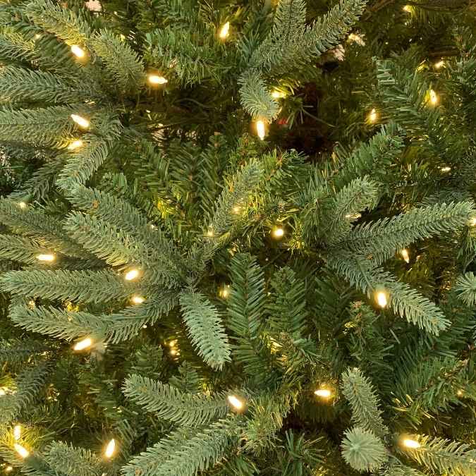 Close-up view of an artificial Christmas tree decorated with warm white string lights.